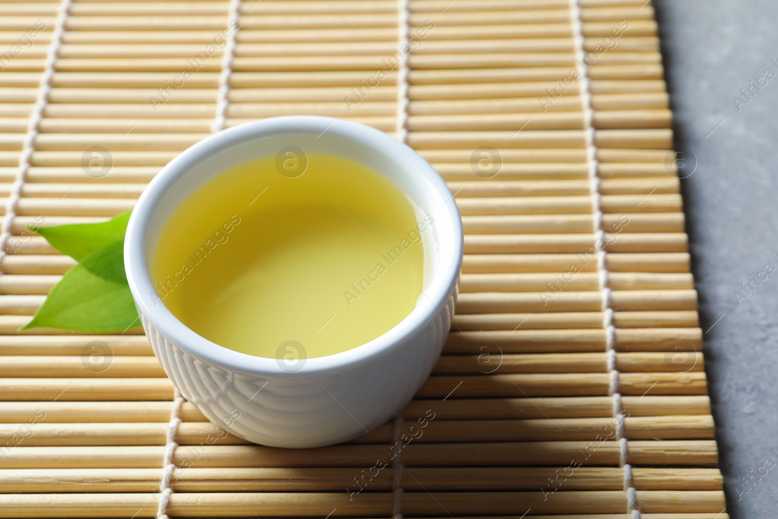 Photo of Cup of freshly brewed oolong tea on bamboo mat, space for text