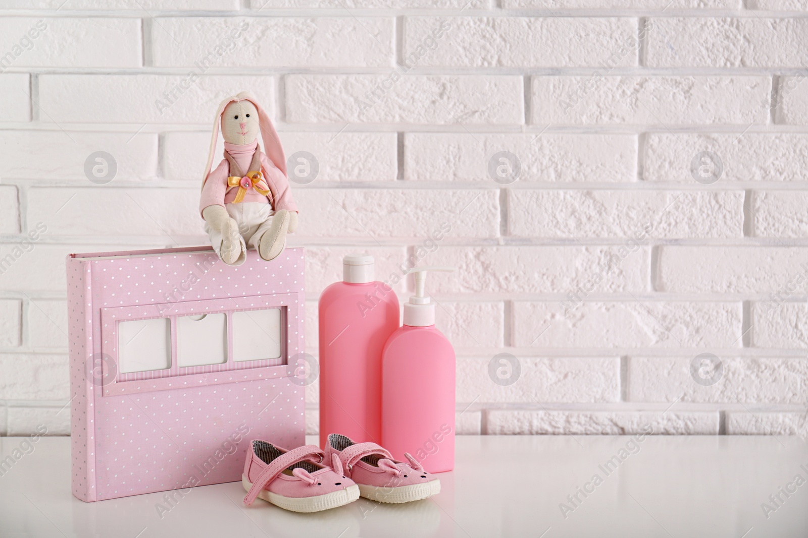 Photo of Stuffed toy with accessories for baby room interior on table near white brick wall