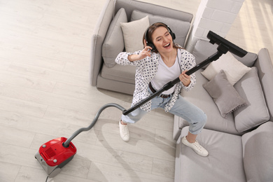 Photo of Young woman having fun while vacuuming at home, above view