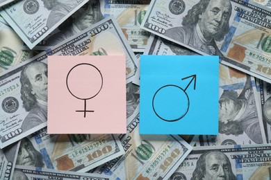 Gender pay gap. Paper notes with male and female symbols on dollar banknotes, flat lay