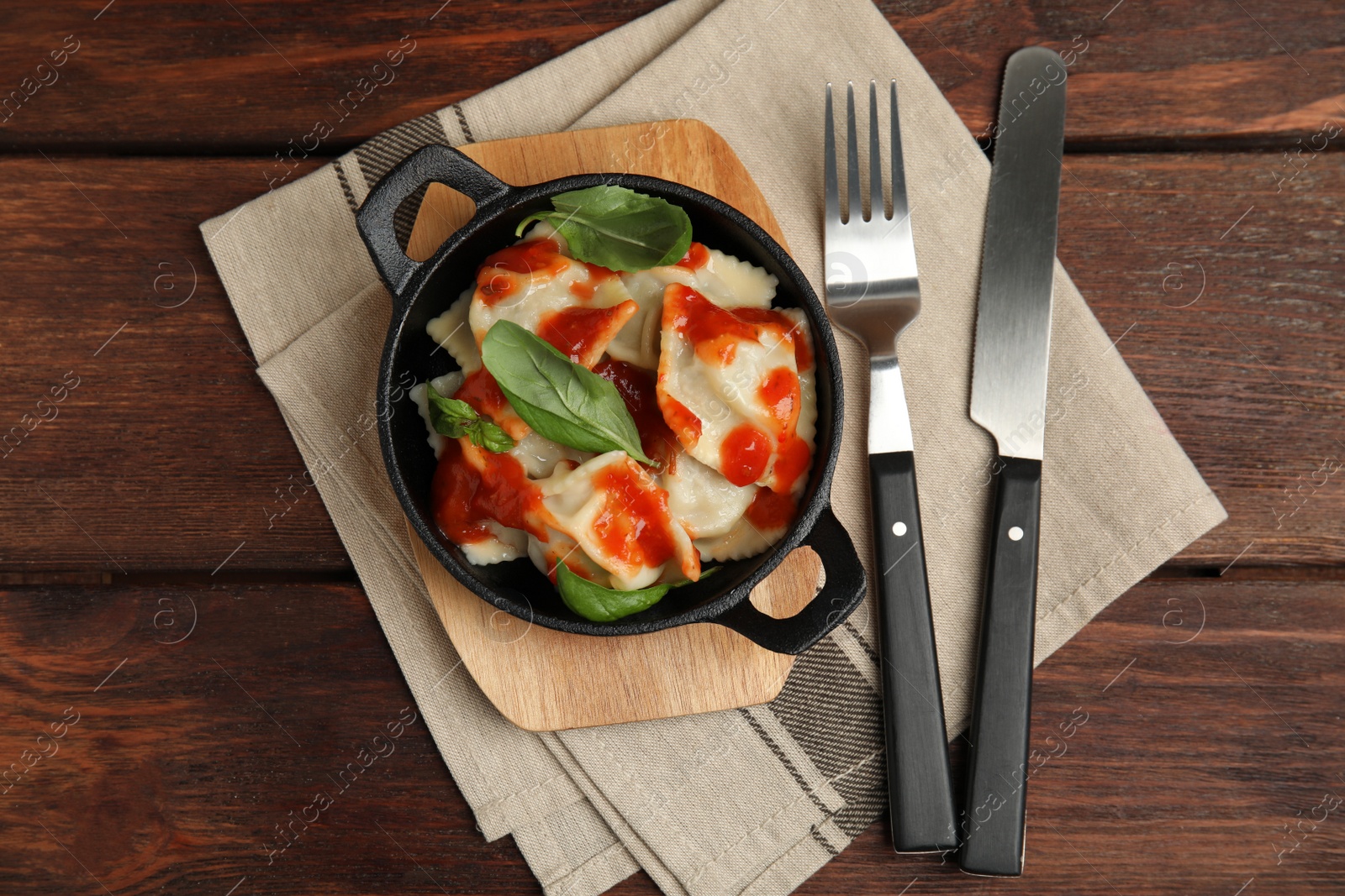 Photo of Tasty ravioli with tomato sauce served on wooden table, flat lay