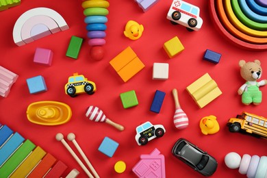 Different children's toys on red background, flat lay