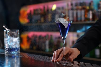 Bartender with fresh alcoholic cocktail at bar counter, closeup. Space for text