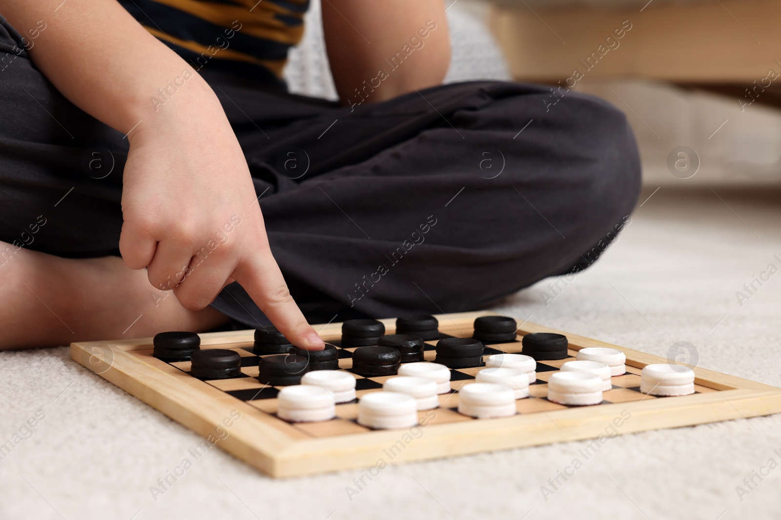 Photo of Playing checkers. Boy thinking about next move on floor in room, closeup
