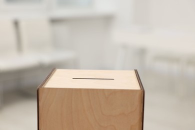 Photo of Wooden ballot box on blurred background, closeup. Space for text