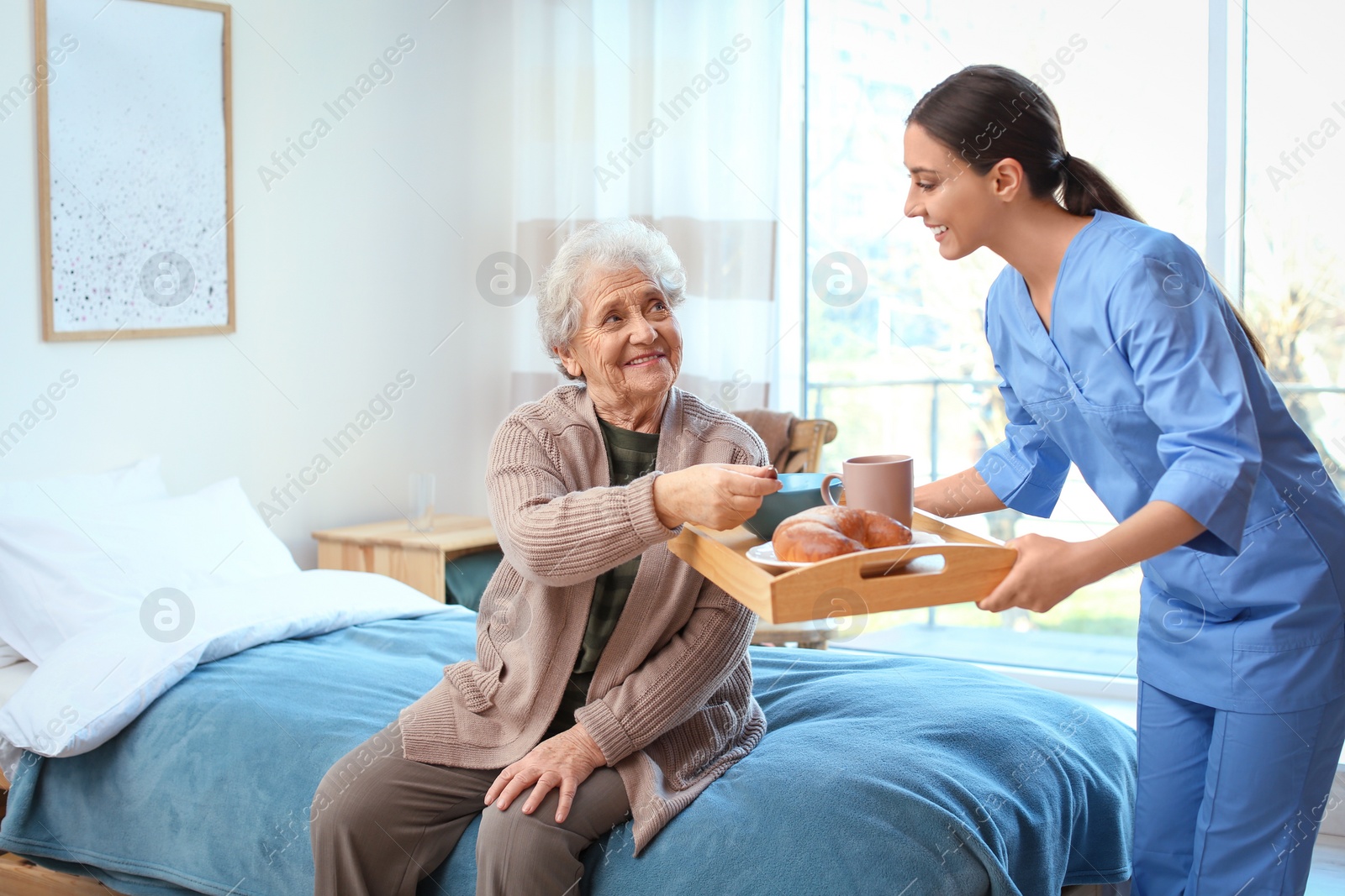 Photo of Care worker serving dinner for elderly woman in geriatric hospice