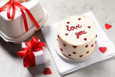 Photo of Bento cake with text Love You, takeaway packaging and gift box on grey table. St. Valentine's day surprise