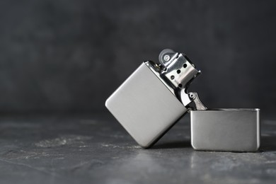 Metallic cigarette lighter on gray textured table against dark background, closeup