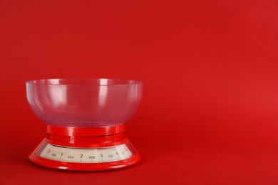Photo of Kitchen scale with plastic bowl on red background, space for text