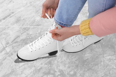 Photo of Woman lacing figure skates on ice, closeup