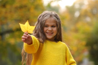 Photo of Portrait of happy girl with autumn dry leaf outdoors