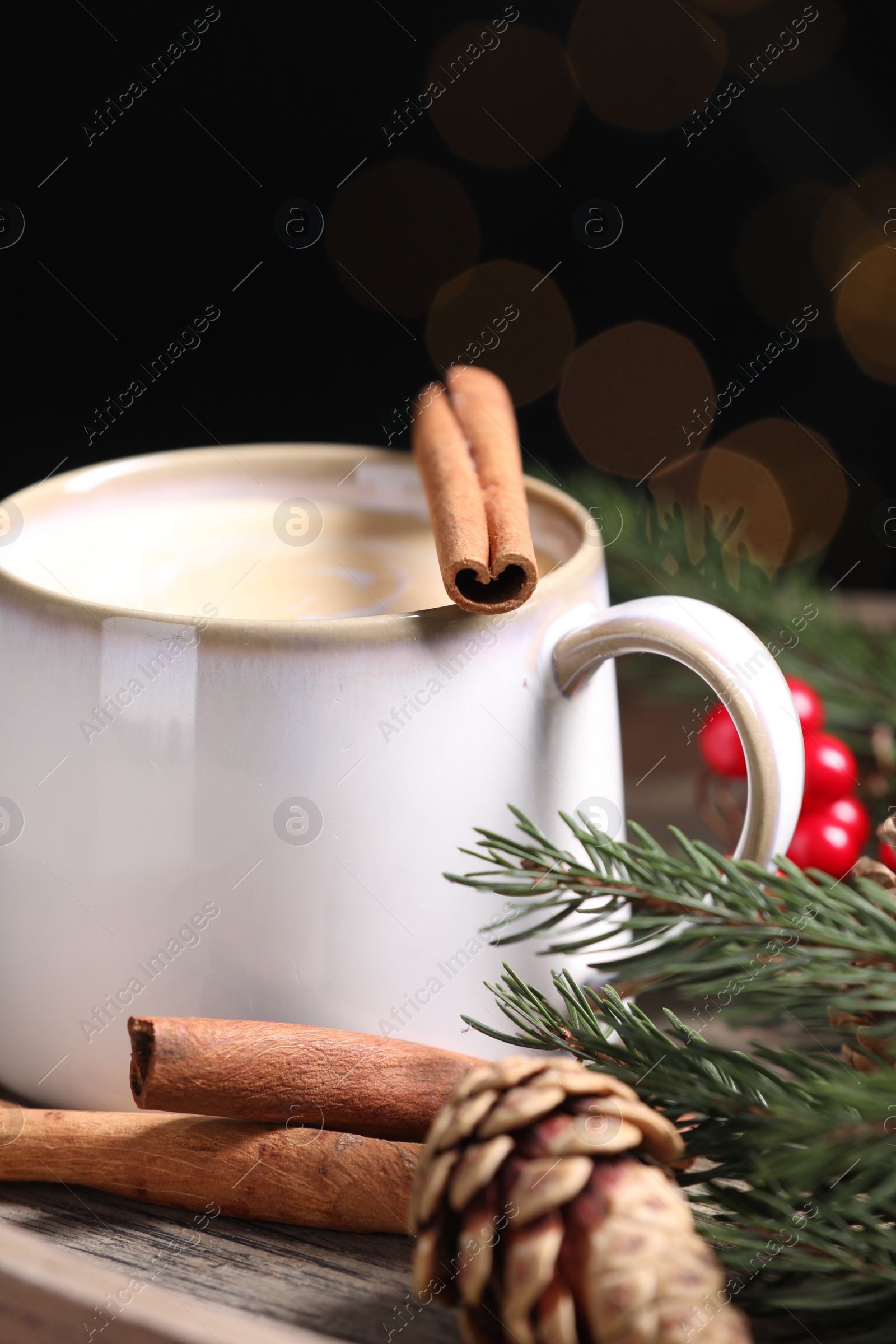 Photo of Tasty eggnog with cinnamon sticks against blurred lights, closeup