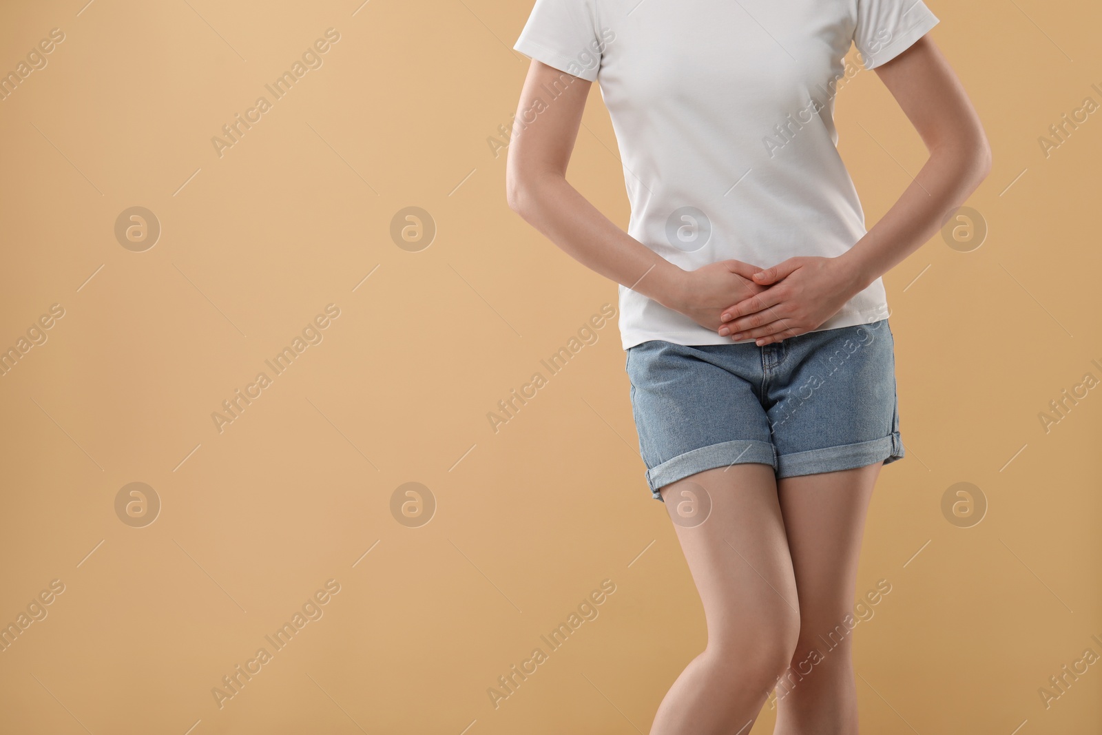 Photo of Woman suffering from cystitis on beige background, closeup. Space for text