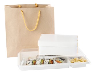 Photo of Food delivery. Containers with delicious sushi rolls near paper package on white background