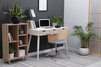 Workplace with laptop, stationery on desk and chair in home office