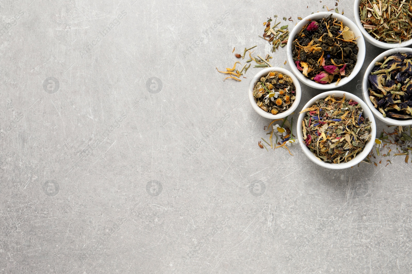 Photo of Flat lay composition with different dry teas on light grey table, space for text