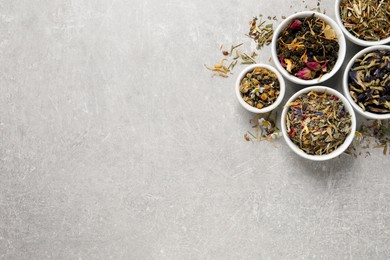 Flat lay composition with different dry teas on light grey table, space for text