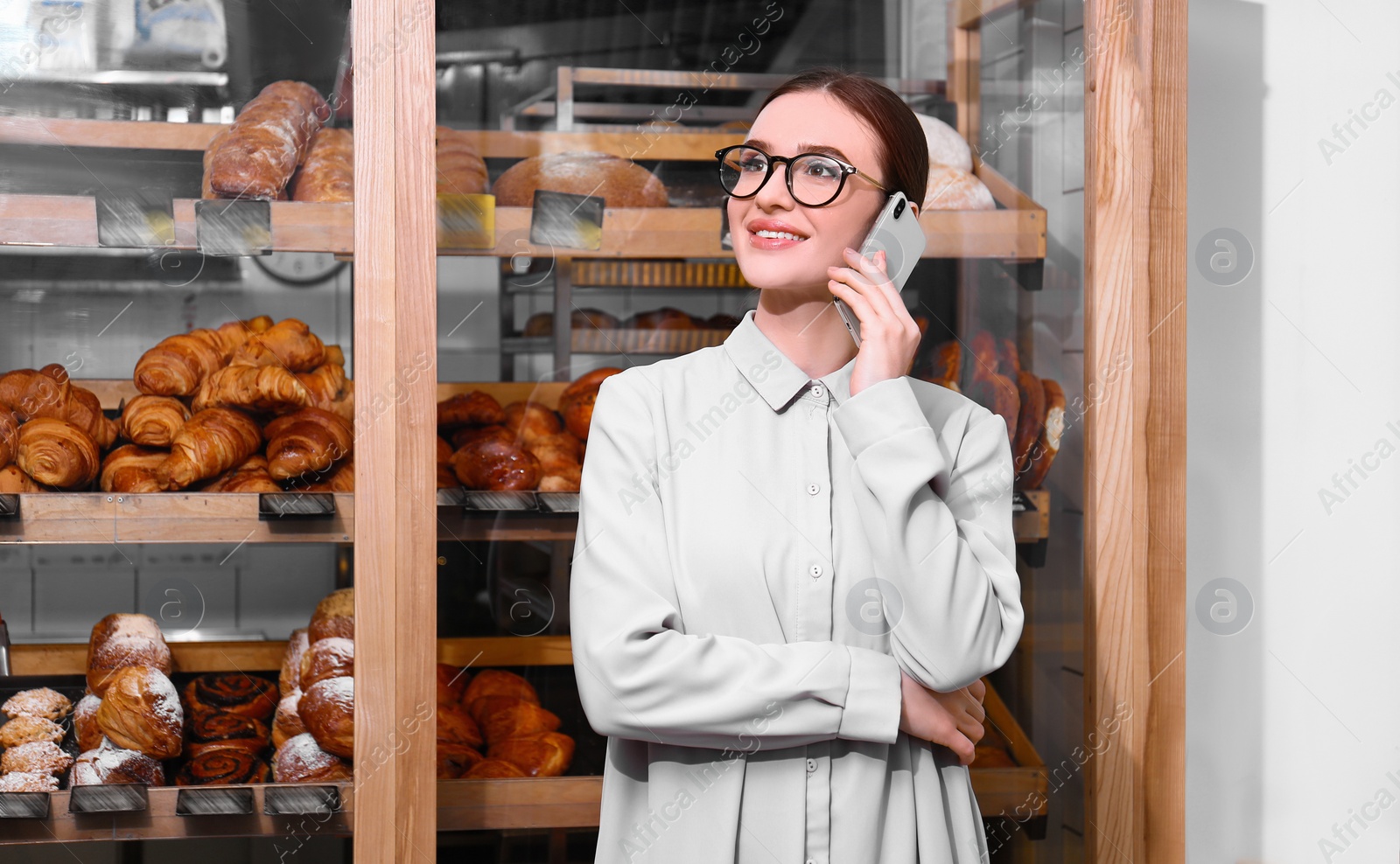 Photo of Female business owner talking on mobile phone in bakery