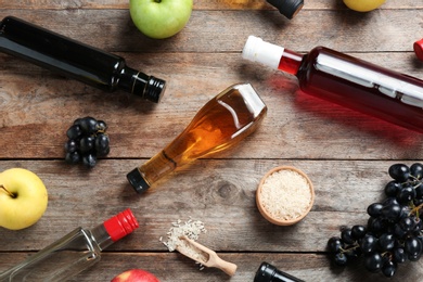 Photo of Flat lay composition with different kinds of vinegar and ingredients on wooden background