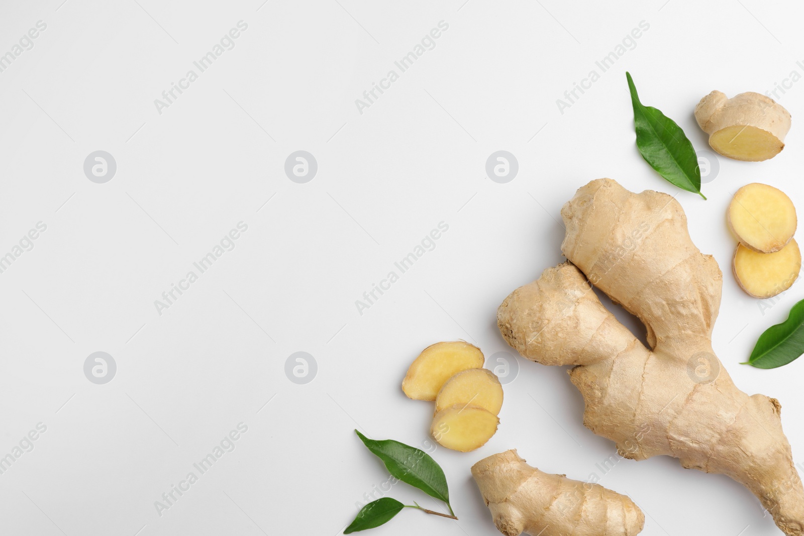 Photo of Fresh ginger with green leaves on white background, flat lay. Space for text