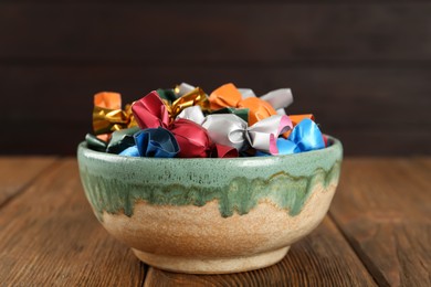 Photo of Candies in colorful wrappers on wooden table, closeup