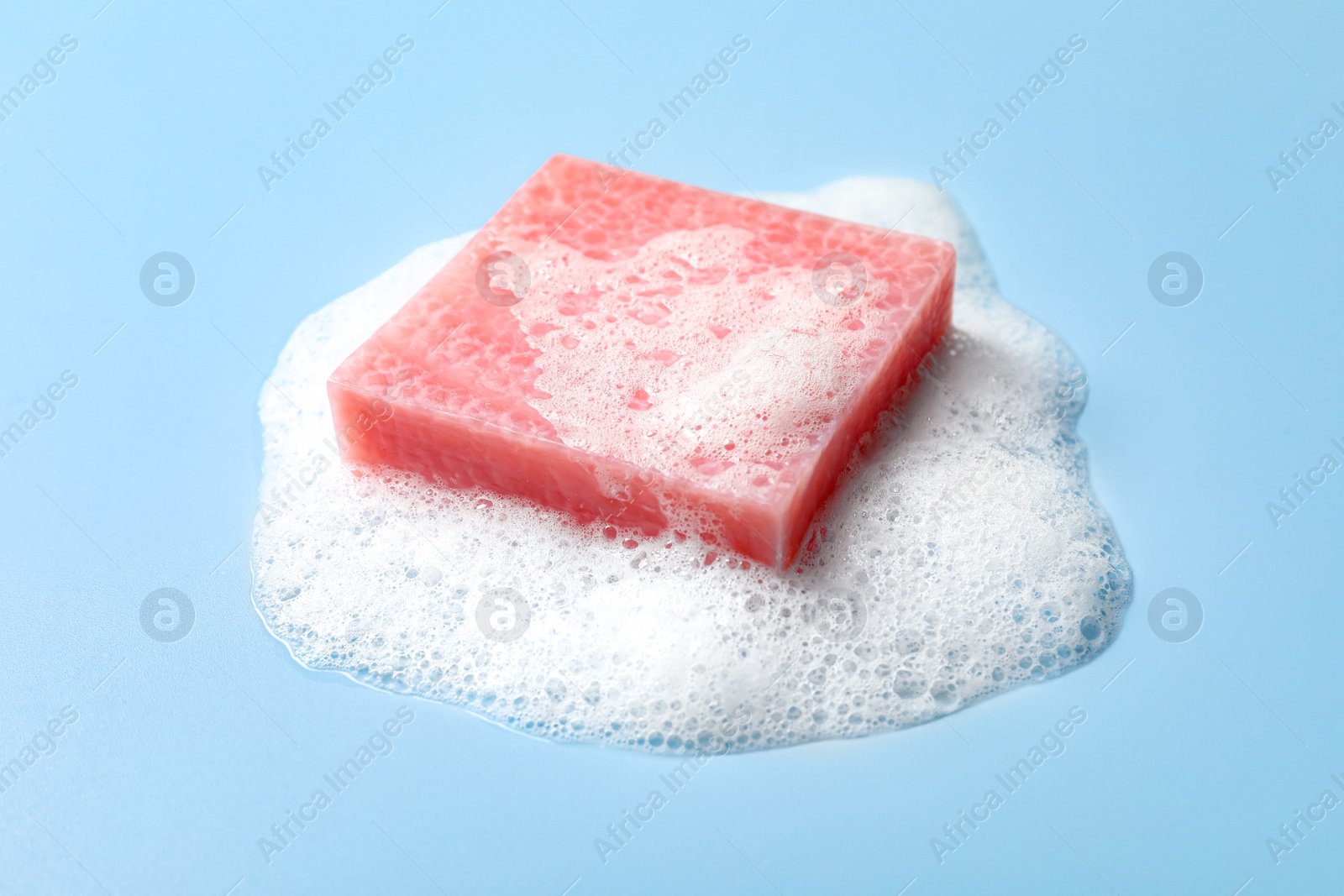 Photo of Soap and fluffy foam on light blue background