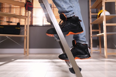 Photo of Person climbing ladder indoors, closeup on feet