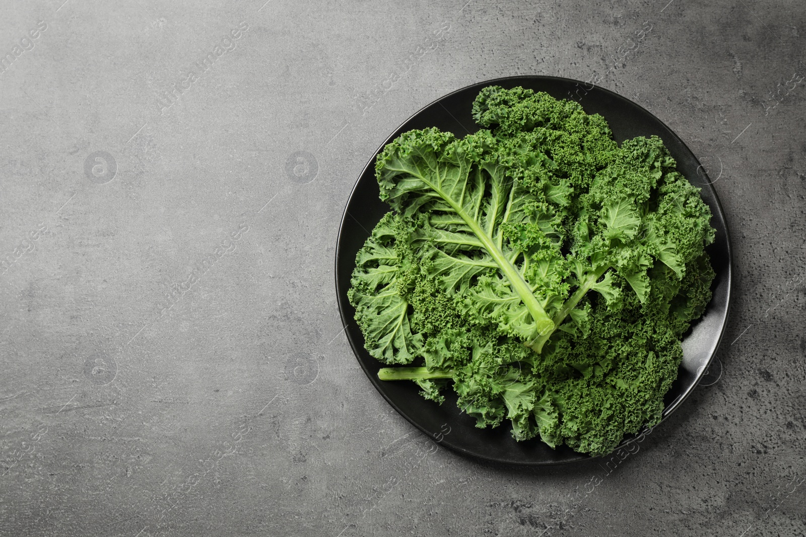 Photo of Fresh kale leaves on grey table, top view. Space for text