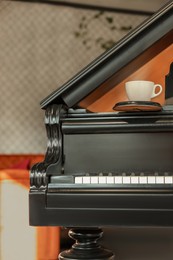 Photo of Cup with coaster on black grand piano in cafe