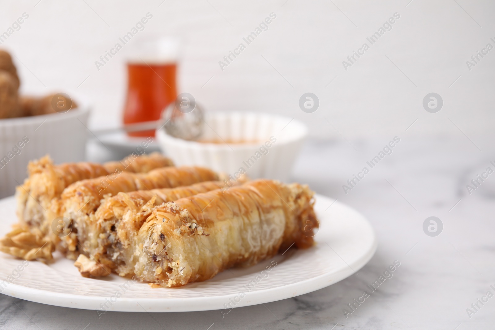 Photo of Eastern sweets. Pieces of tasty baklava on white marble table, closeup. Space for text