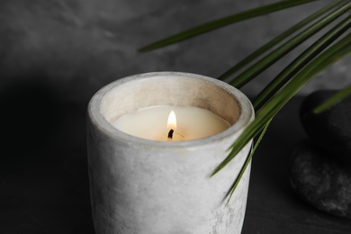 Burning candle, spa stones and palm leaf on grey background