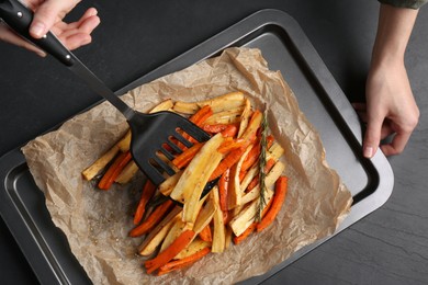 Photo of Cooker near baking pan with tasty parsnip and bell pepper at dark grey table, top view