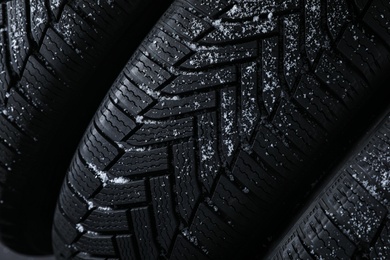 Snowy new winter tires as background, closeup
