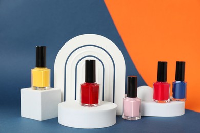 Photo of Stylish presentation of bright nail polishes in bottles on color background