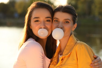 Photo of Beautiful young women blowing bubble gums outdoors