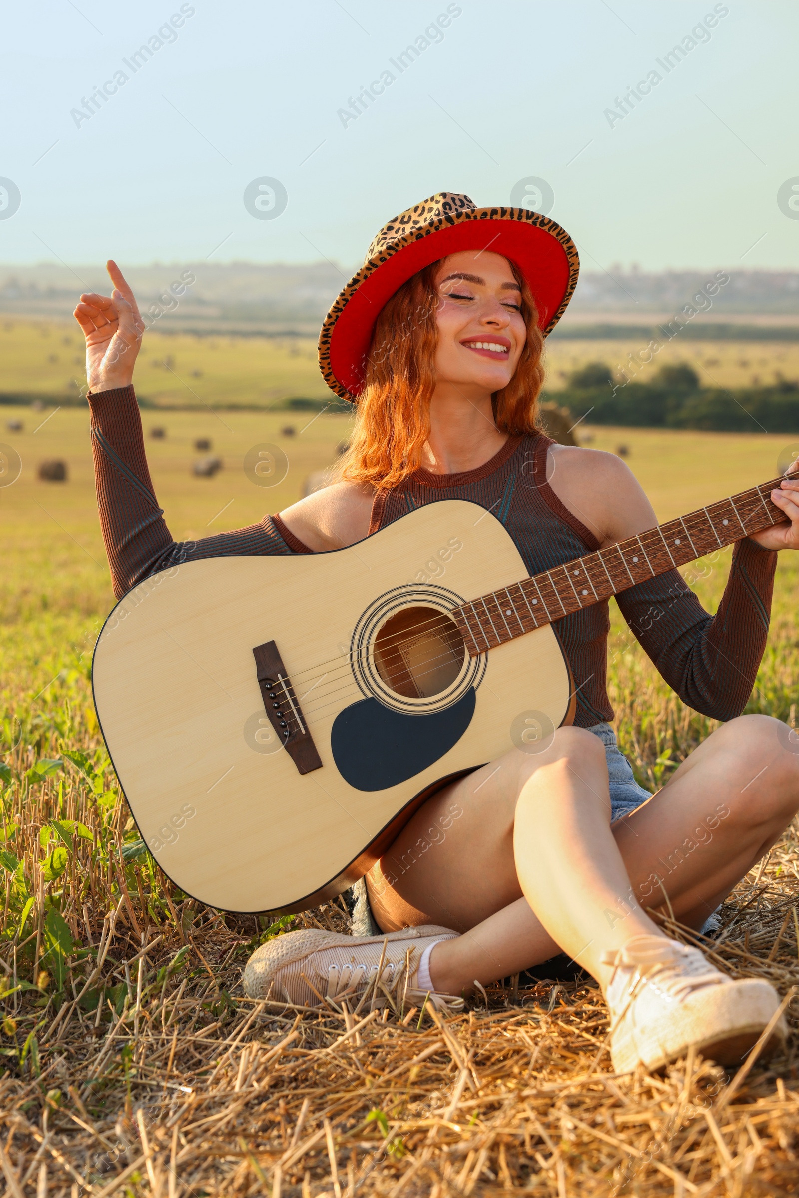Photo of Beautiful happy hippie woman with guitar in field