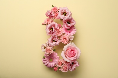 Photo of Number 8 made of beautiful pink flowers on beige background, flat lay. International Women's day