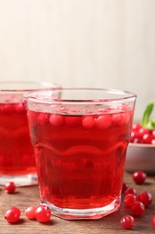 Tasty cranberry juice in glasses and fresh berries on wooden table, closeup