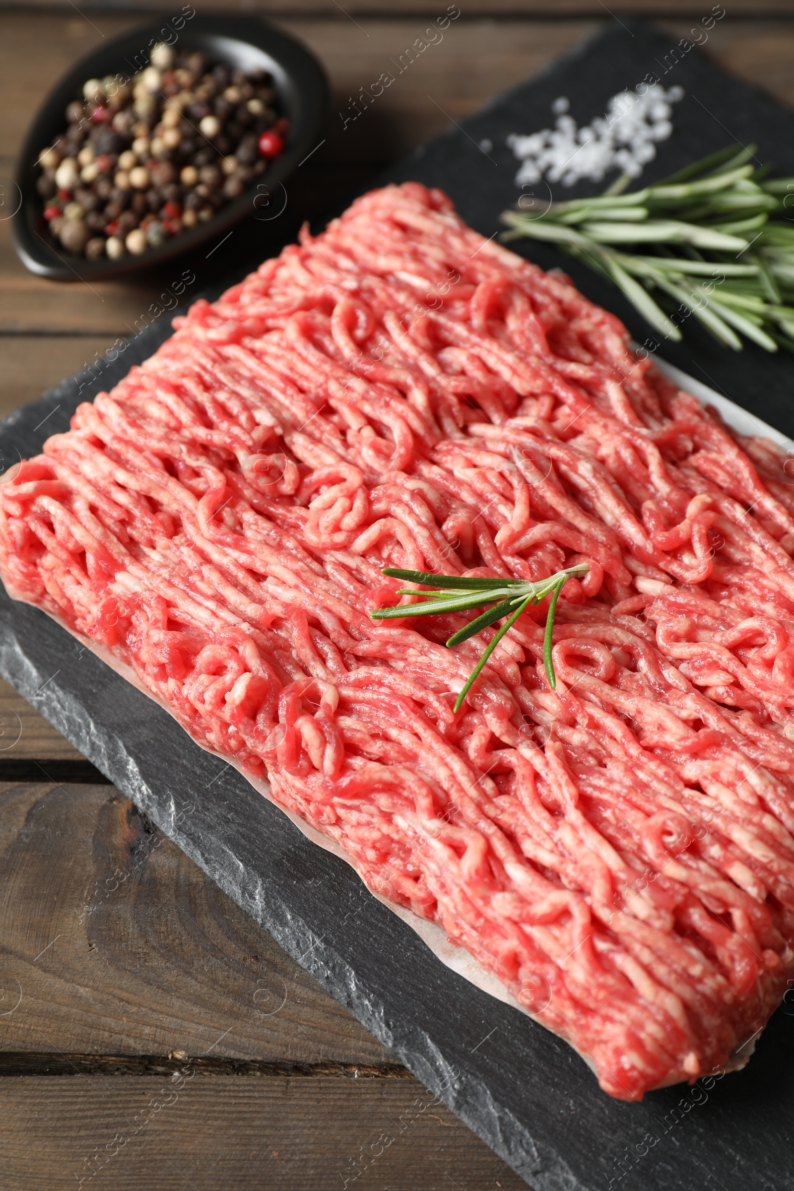 Photo of Raw ground meat, spices and rosemary on wooden table