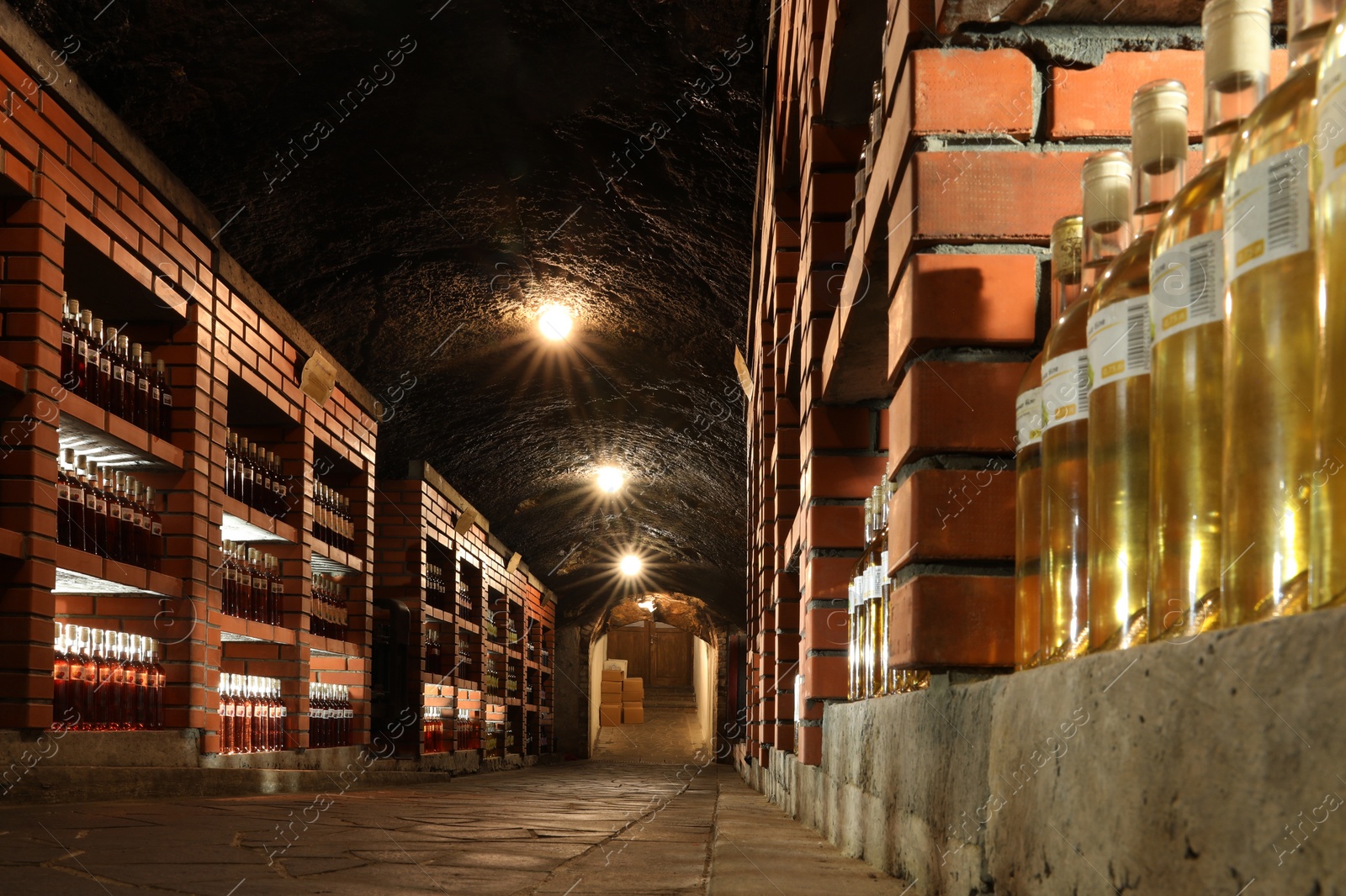 Photo of Beregove, Ukraine - June 23, 2023: Many bottles of alcohol drinks on shelves in cellar, low angle view