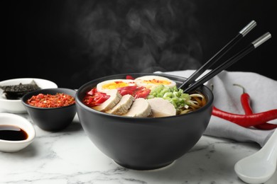 Image of Delicious hot ramen in bowl on white marble table against black background, closeup. Noodle soup