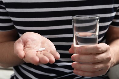 Photo of Man with glass of water and pill, closeup