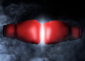 Image of Boxing gloves opposing each other against black background