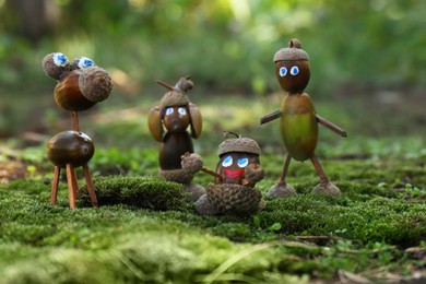 Cute figures made of acorns on green moss outdoors