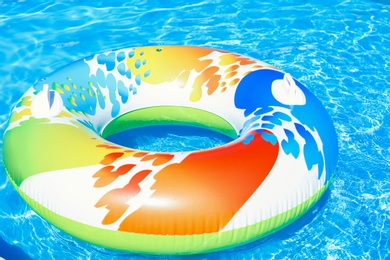 Colorful inflatable ring floating in swimming pool on sunny day