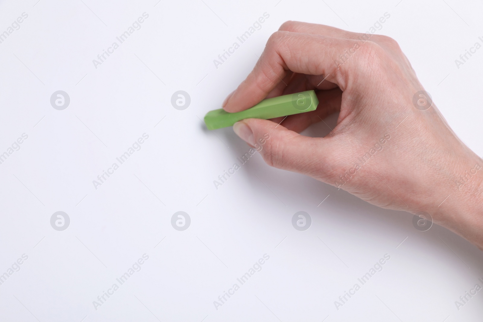 Photo of Woman drawing on white paper with pastel, top view. Space for text