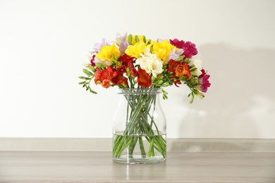 Photo of Beautiful bright freesia flowers in vase on table