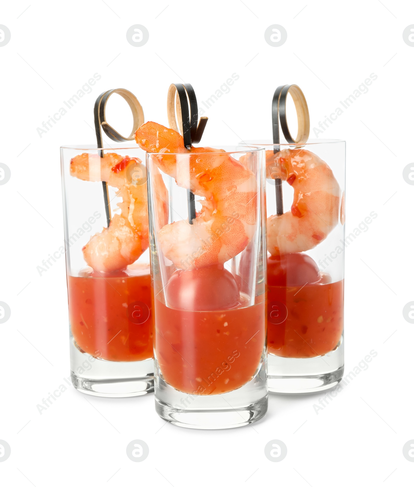 Photo of Tasty canapes with shrimps, tomatoes and sauce in shot glasses isolated on white