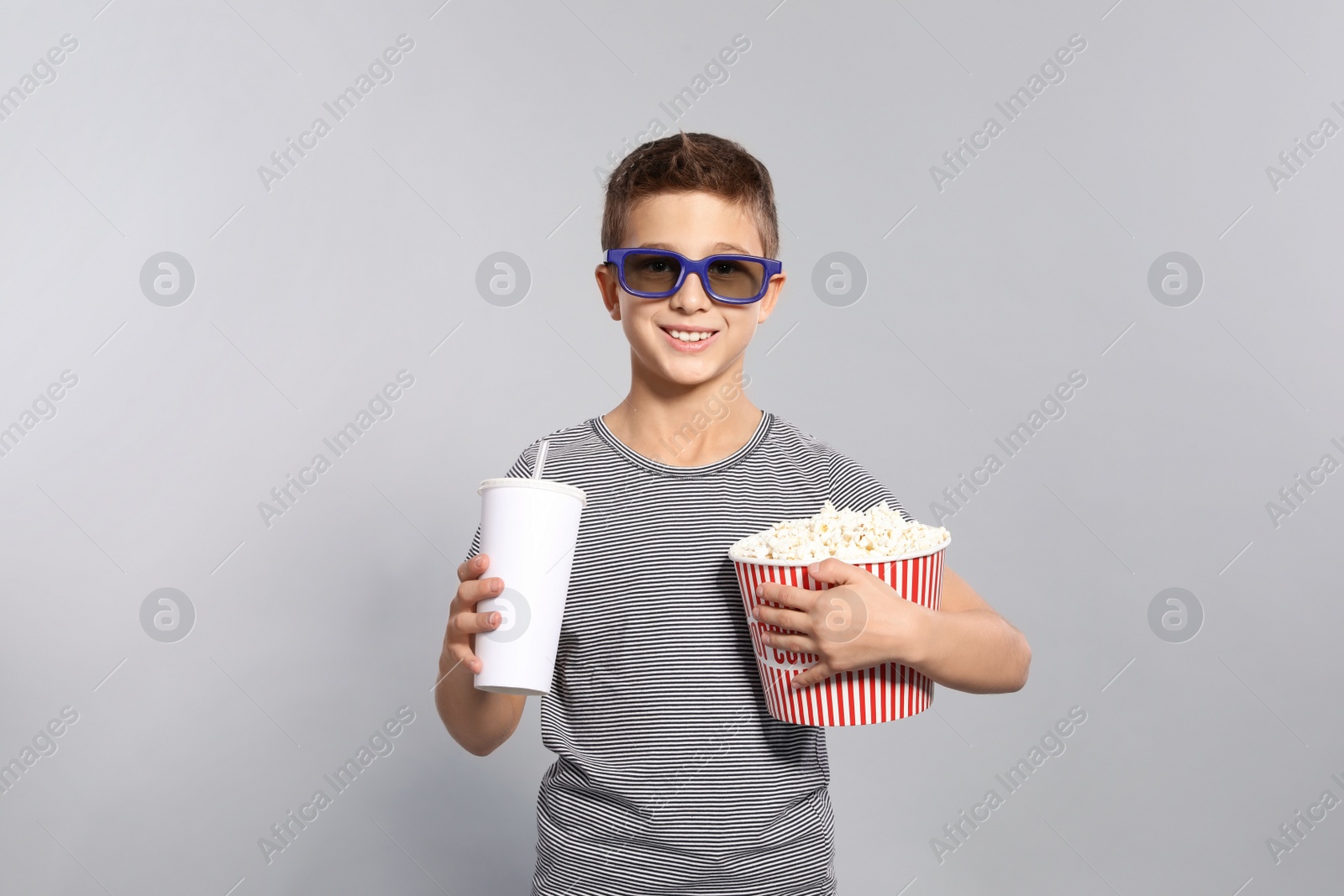 Photo of Boy with 3D glasses, popcorn and beverage during cinema show on grey background