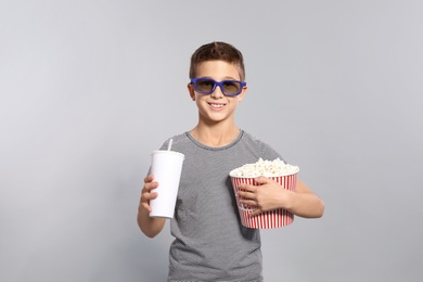 Photo of Boy with 3D glasses, popcorn and beverage during cinema show on grey background
